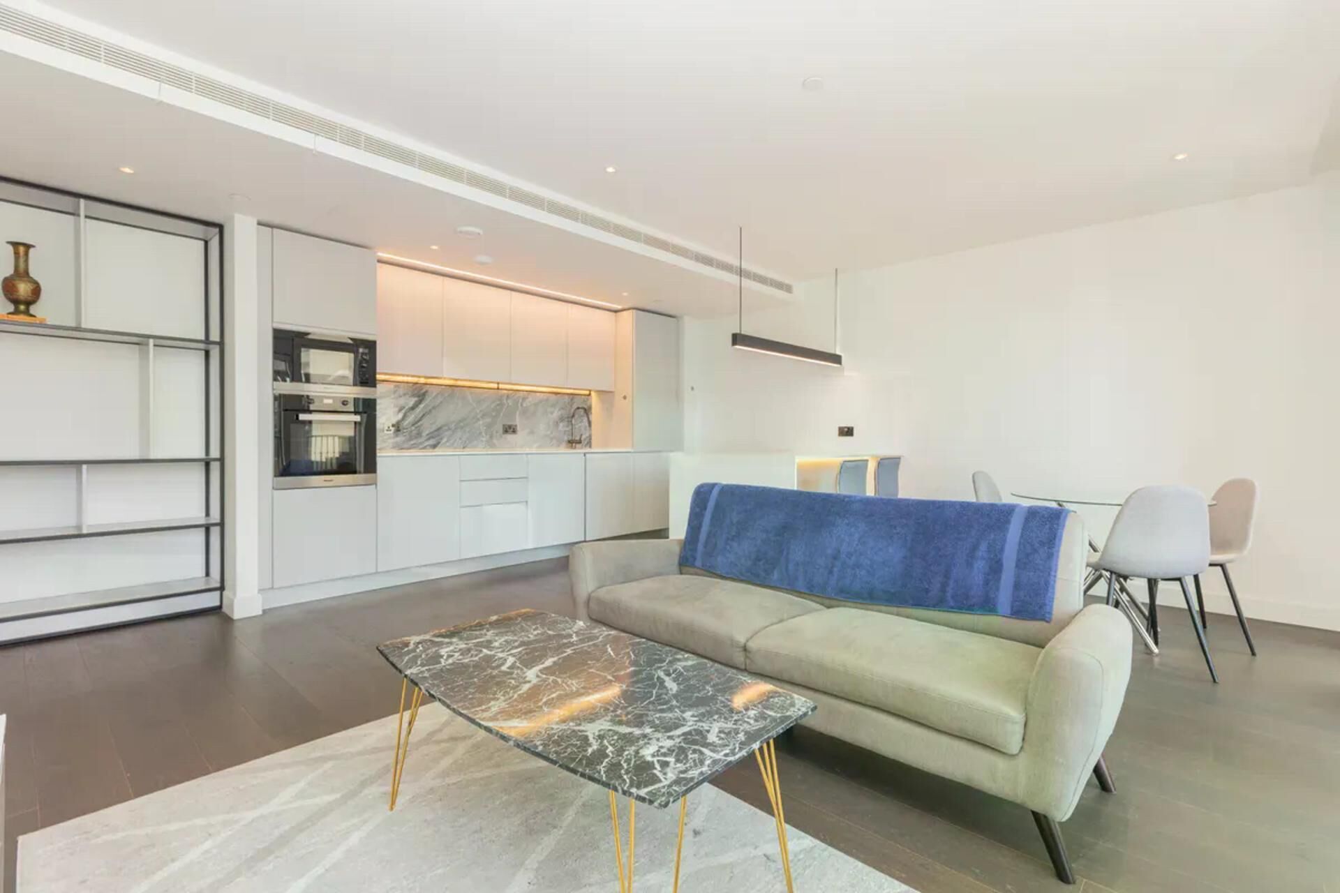 A modern living room with a sofa, a coffee table, and a dining area with chairs.