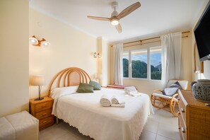 Ein Schlafzimmer mit Bett, Nachttisch, Lampe und Deckenventilator.