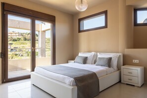 A bedroom with a bed, bedside tables, a window, and a balcony. - Villa Mononaftis (Heraklion)