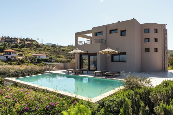 Un edificio moderno con piscina, zona de estar al aire libre y vistas a un paisaje montañoso.