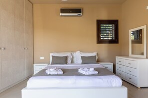 A hotel room with a bed, bedside tables, a wardrobe, and a window with blinds. - Villa Mononaftis (Heraklion)