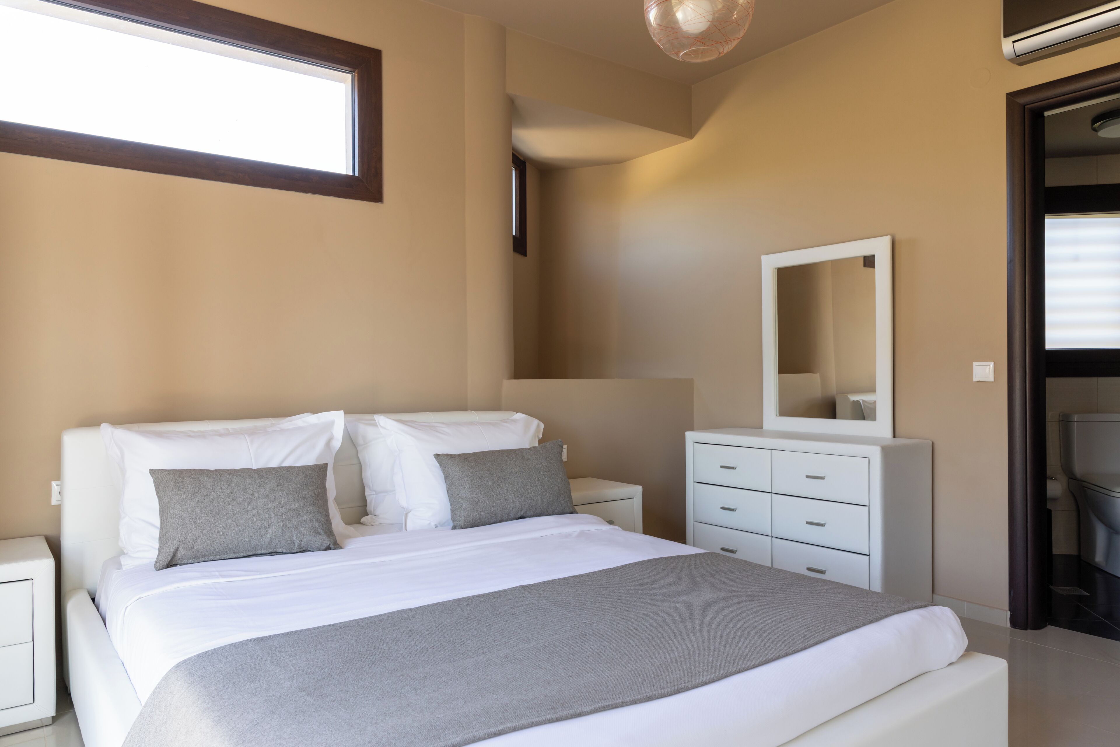 Une chambre à coucher avec un lit, des tables de chevet, une commode et un miroir.
