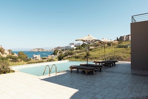 A pool area with lounge chairs and a view of the sea. - Villa Mononaftis (Heraklion)