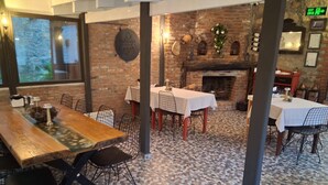 A restaurant interior with brick walls, tiled flooring, and multiple tables with chairs. - ADATEPE OTEL KAZDAĞLARI (Ayvacik)