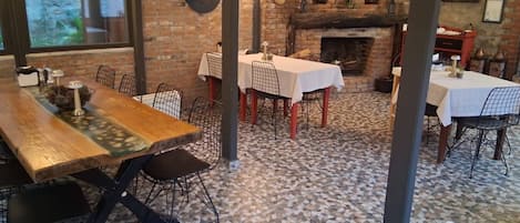 A restaurant interior with brick walls, tiled flooring, and multiple tables with chairs.