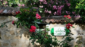 A stone wall with a sign for 'adatepe hotel' and blooming pink roses. - ADATEPE OTEL KAZDAĞLARI (Ayvacik)