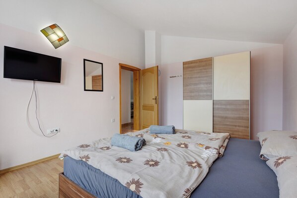 A bedroom with a bed, a TV, a wardrobe, and a mirror.