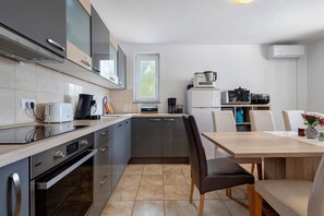 A compact kitchen with modern appliances, a dining area with a table and chairs, and a window providing natural light.