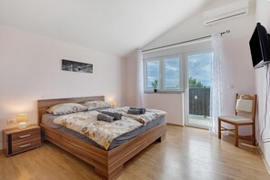 A bedroom with a wooden bed, bedside tables, a chair, and a window with a view.