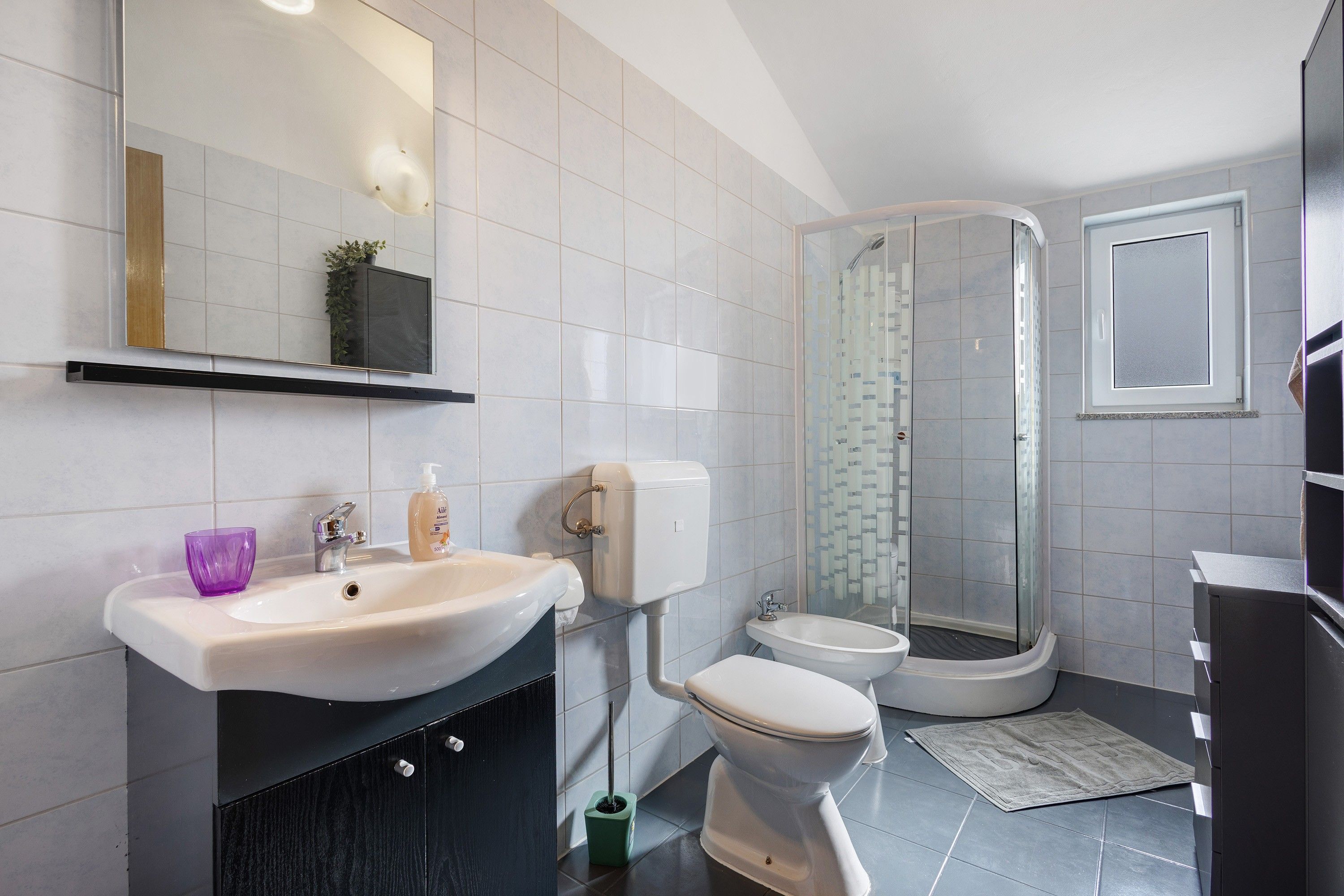A modern bathroom with a white sink, toilet, and shower.