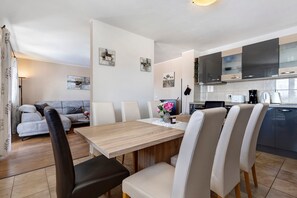 A modern kitchen with a dining area, featuring a wooden table, chairs, and artwork on the walls.
