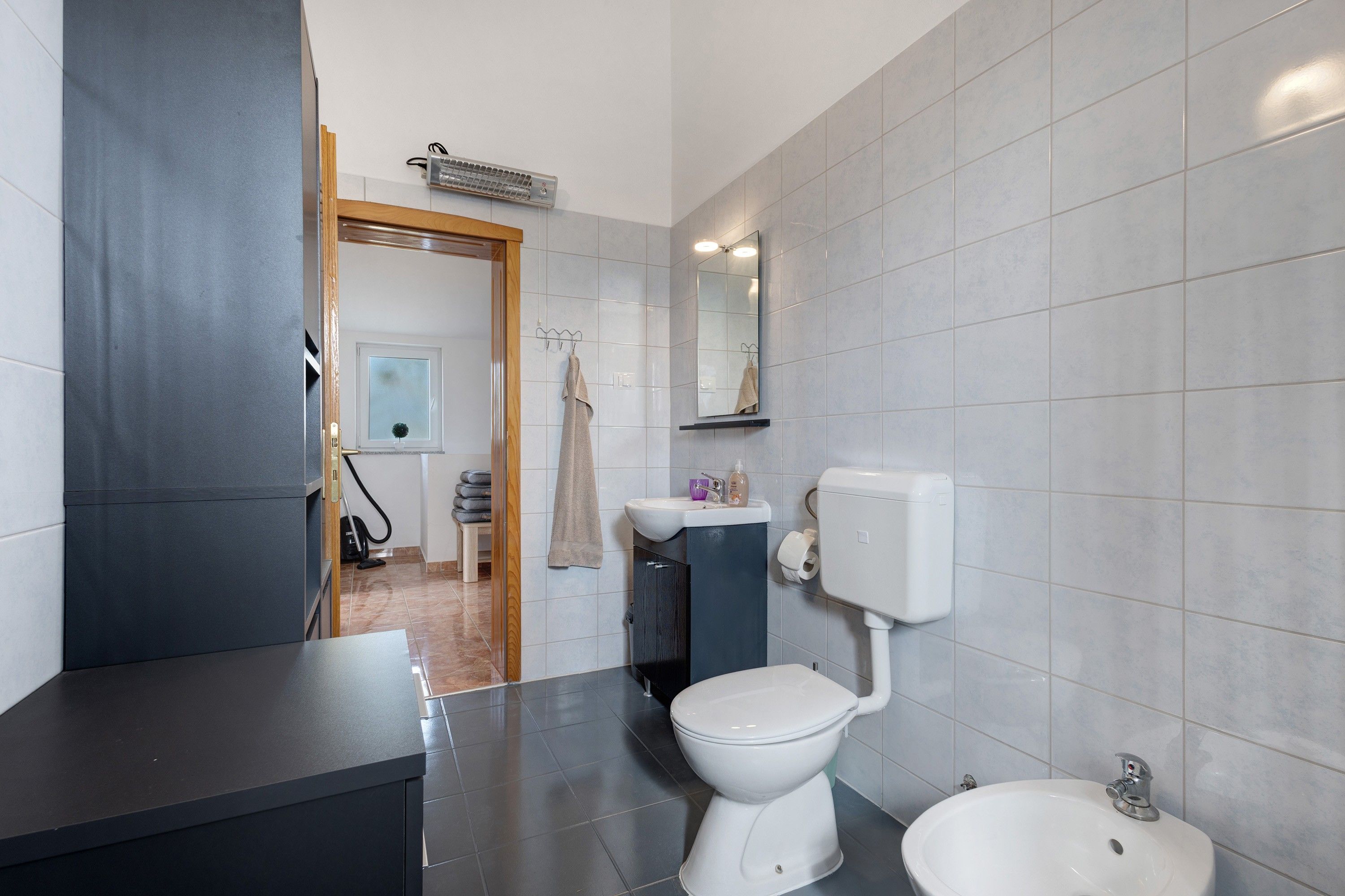Un baño moderno con inodoro, bidé, lavamanos y espejo.