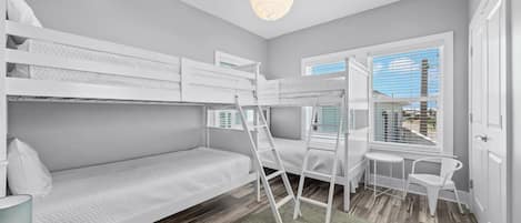 Habitación con literas, un escritorio, una silla, una ventana con persianas y una lámpara colgante.