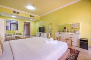 A hotel room with a large bed, a desk, a television, and a wardrobe. - Canalfront Studio Steps from the Waterfront Promenade and Cricket Stadium (Dubai)