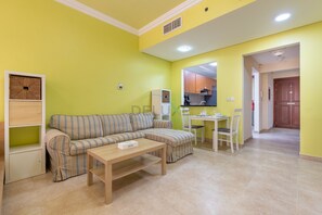 A living room with a sectional sofa, a coffee table, and a dining area with a table and chairs. - Canalfront Studio Steps from the Waterfront Promenade and Cricket Stadium (Dubai)