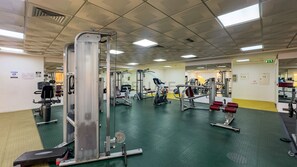 A gym with various exercise equipment, including weight machines and cardio machines. - Canalfront Studio Steps from the Waterfront Promenade and Cricket Stadium (Dubai)