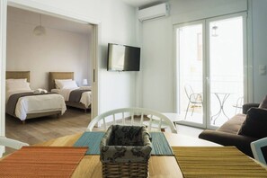 A hotel room with two beds, a TV, a balcony with chairs, and a dining area with a table and chairs. - Comfort Zone Apartment in the heart of Athens (Athina)