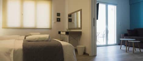 Habitación de hotel con cama, escritorio, silla, espejo y vistas al exterior.