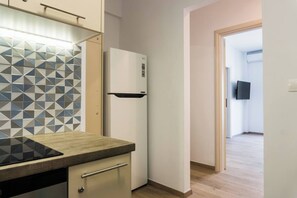 A kitchen with a modern design, featuring a patterned backsplash, a built-in oven, and a refrigerator. - Comfort Zone Apartment in the heart of Athens (Athina)