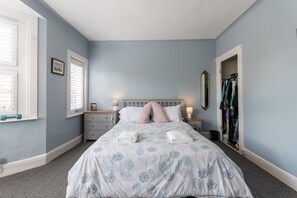 Un dormitorio con cama, mesitas de noche, armario y ventana con persianas.