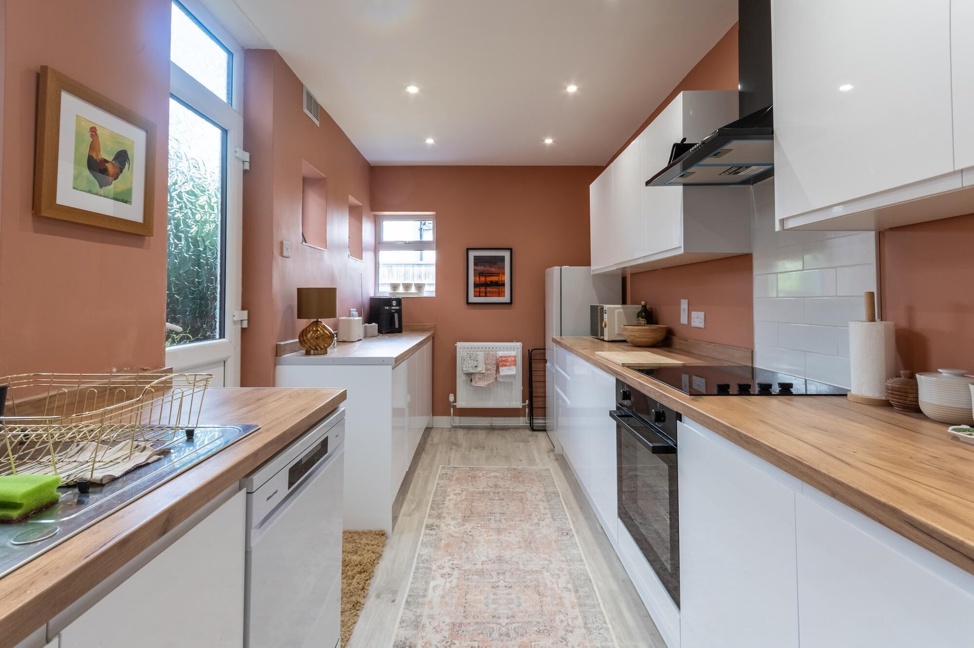 Une cuisine moderne avec des meubles blancs, un plan de travail en bois et un four encastré.