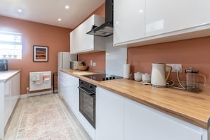 A modern kitchen with white cabinetry, a wooden countertop, and a built-in oven.