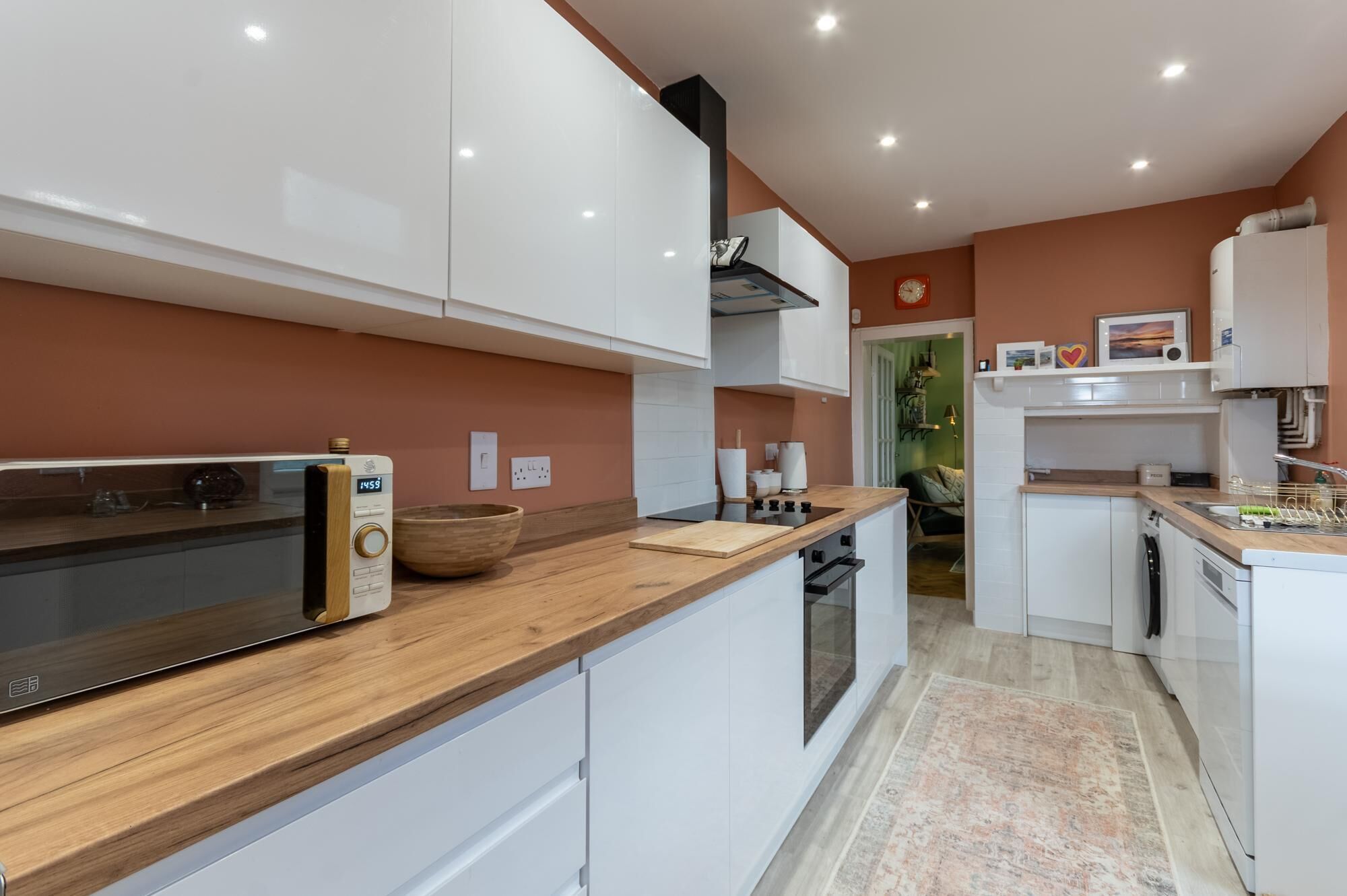 A modern kitchen with white cabinetry, a wooden countertop, and a built-in oven.