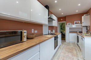 A modern kitchen with white cabinetry, a wooden countertop, and a built-in oven.
