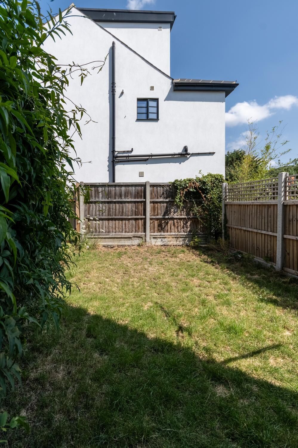 A white two-story house with a fenced backyard, a wooden fence, and a small window.
