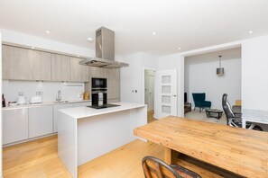 A modern kitchen with white cabinetry, a built-in oven, and a central island. - Lovely 2 Bed flat with parking - Pass the Keys (Leamington Spa)