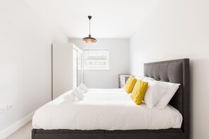 Ein Schlafzimmer mit einem Bett, einem Nachttisch, einem Kleiderschrank und einem Fenster.