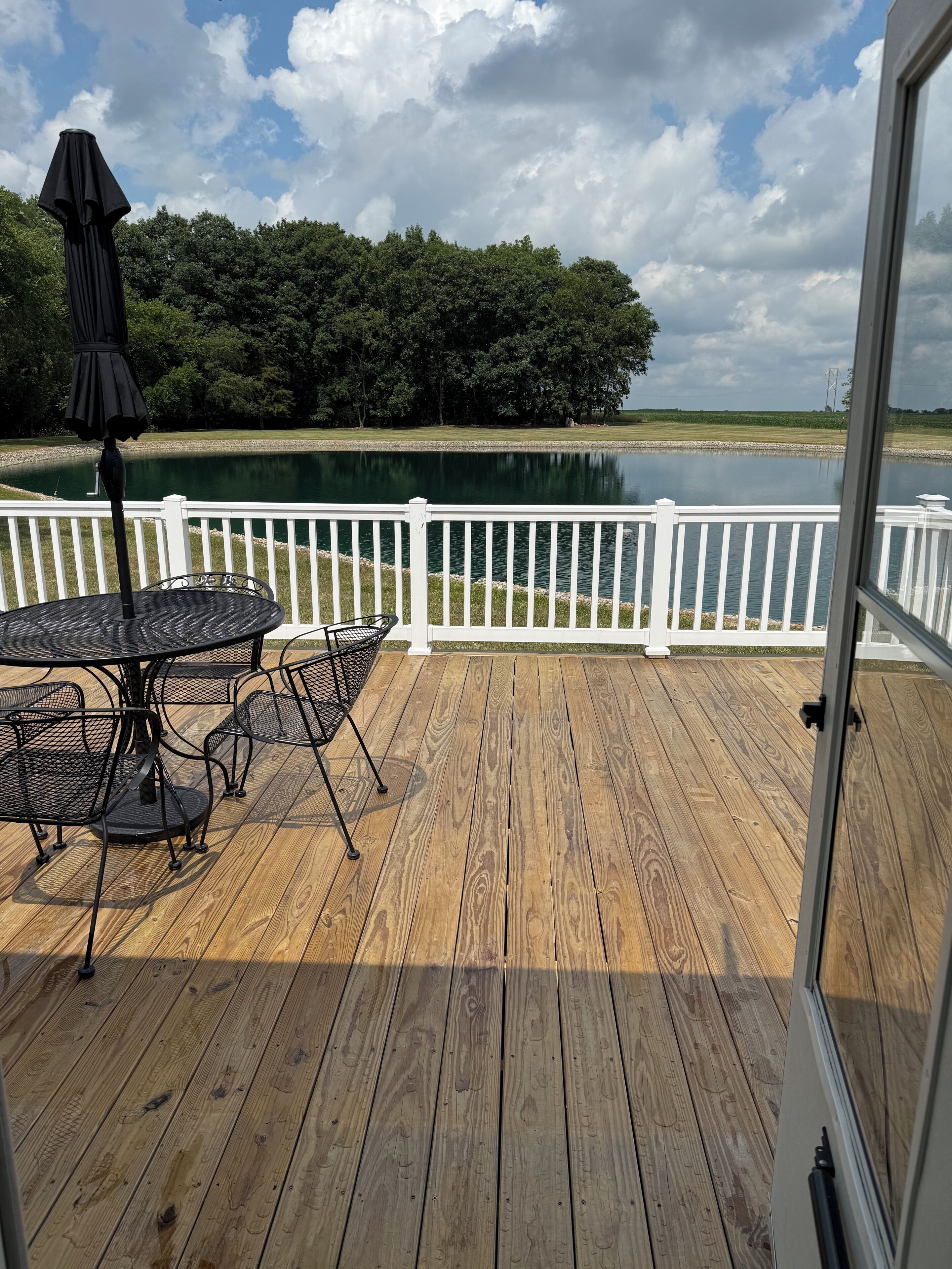 Une terrasse en bois avec une table et des chaises, donnant sur un lac et une forêt.