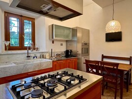 Una cocina moderna con estufa a gas, electrodomésticos de acero inoxidable, armarios de madera y un comedor con mesa y sillas.