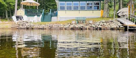 A lakeside cabin with a dock, outdoor seating, and a covered area.