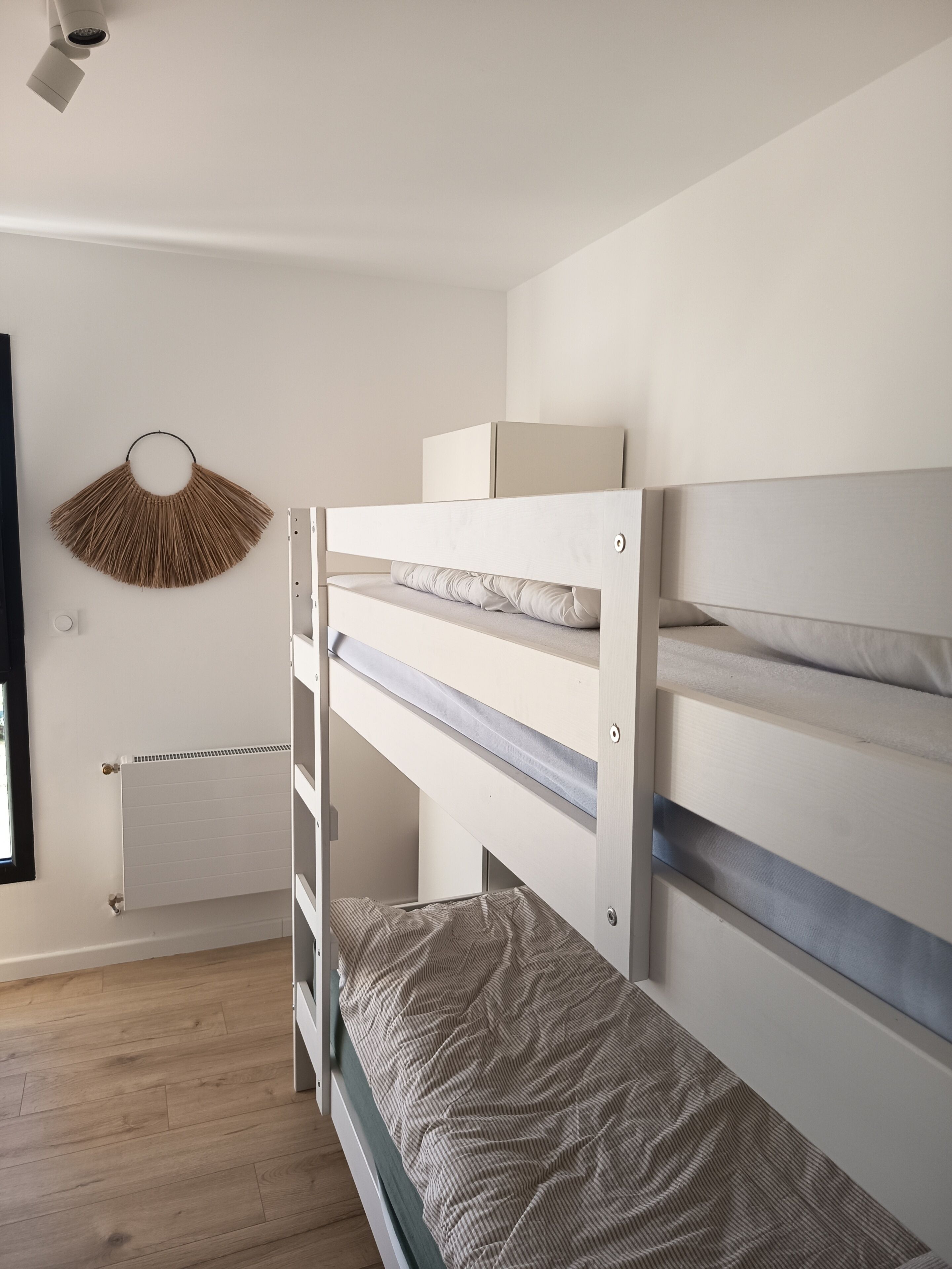 Ein Stockbett mit Kopfteil, einem Heizkörper und einem Wanddekor.