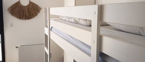 A bunk bed with a headboard, a radiator, and a wall-mounted decorative item.