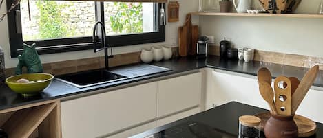 A modern kitchen with a black countertop, a built-in oven, and a window with blinds.