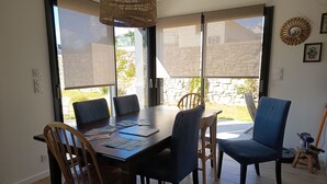 A dining area with a large table, chairs, and a view through the glass doors. - Sea view house 5 minutes walk from the beach and coastal paths. (Saint-Pol-de-Léon)