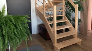 A modern interior with a wooden staircase, a dark door, and a potted fern. - Sea view house 5 minutes walk from the beach and coastal paths. (Saint-Pol-de-Léon)