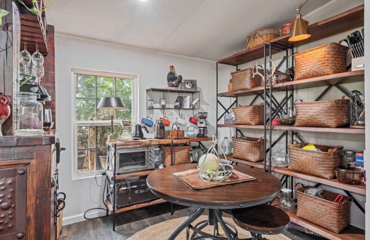 A kitchen with a round wooden table, shelves with baskets, and vintage appliances.