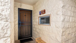 Una puerta con una reja de metal, un banco de madera y una ventana con un letrero encima.