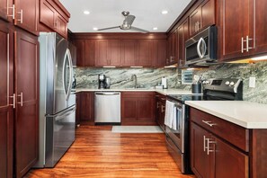A modern kitchen with wooden cabinets, stainless steel appliances, and a marble backsplash. - New Listing Keauhou Punahele C202, Ocean Views, Pool (Kailua)