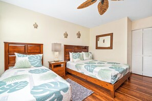 A bedroom with two wooden beds, a nightstand, a mirror, and a wardrobe. - New Listing Keauhou Punahele C202, Ocean Views, Pool (Kailua)
