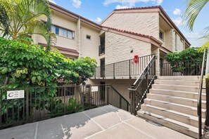 A residential building with a stone facade, a gated entrance, and a staircase leading to the upper floors. - New Listing Keauhou Punahele C202, Ocean Views, Pool (Kailua)