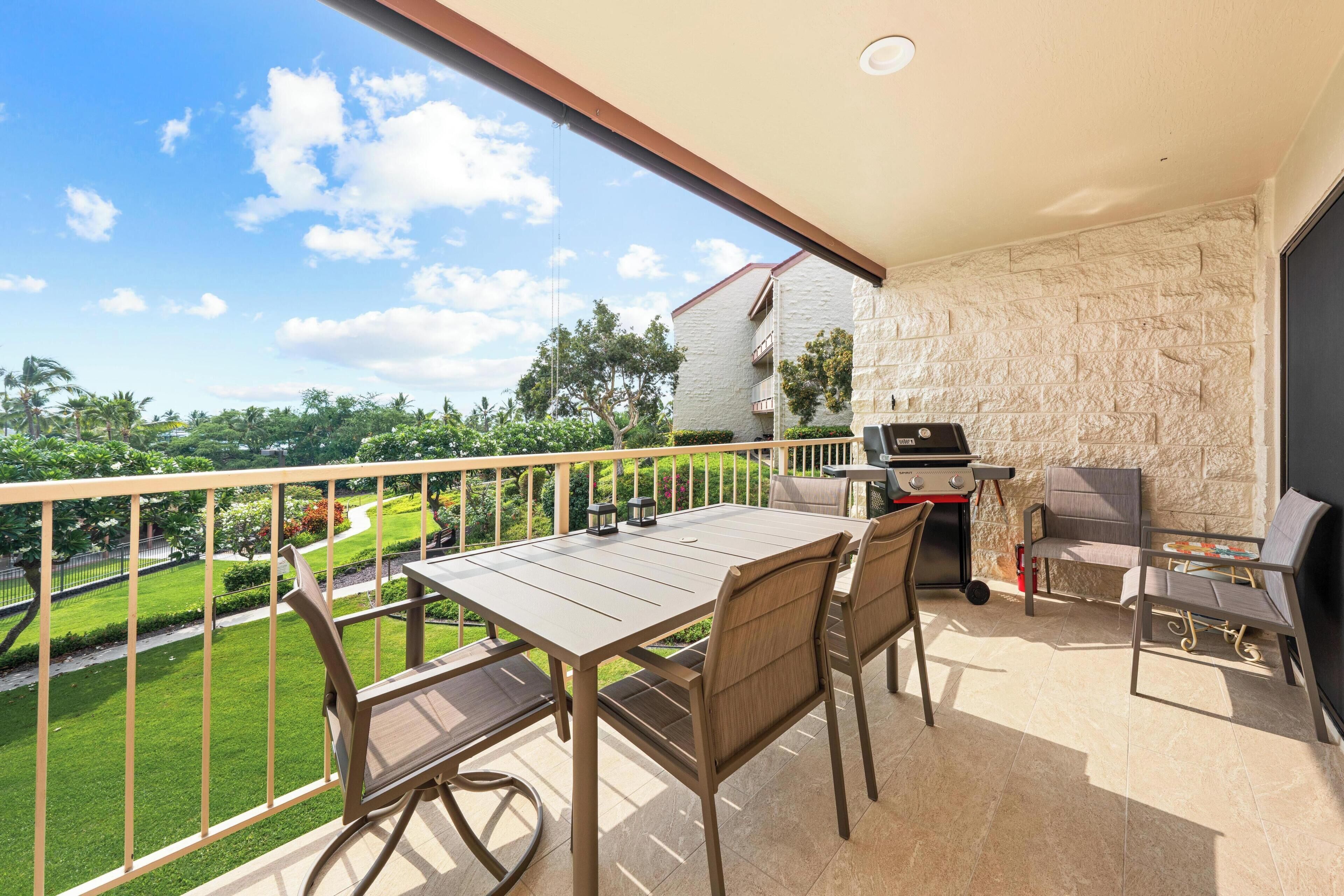 Ein Balkon mit Tisch und Stühlen, einem Grill und Blick auf eine grüne Landschaft.