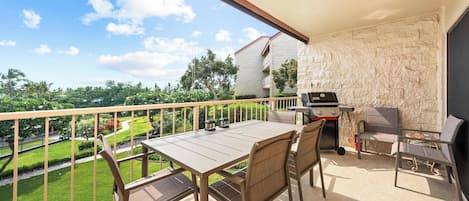 Ein Balkon mit Tisch und Stühlen, einem Grill und Blick auf eine grüne Landschaft.