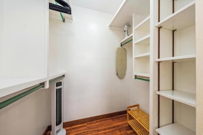 Un vestidor con estantes blancos, un banco de madera y un tapiz de pared estampado.