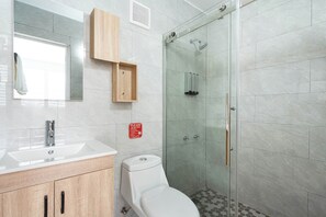Une salle de bain moderne avec une douche à parois de verre, des toilettes et un lavabo.