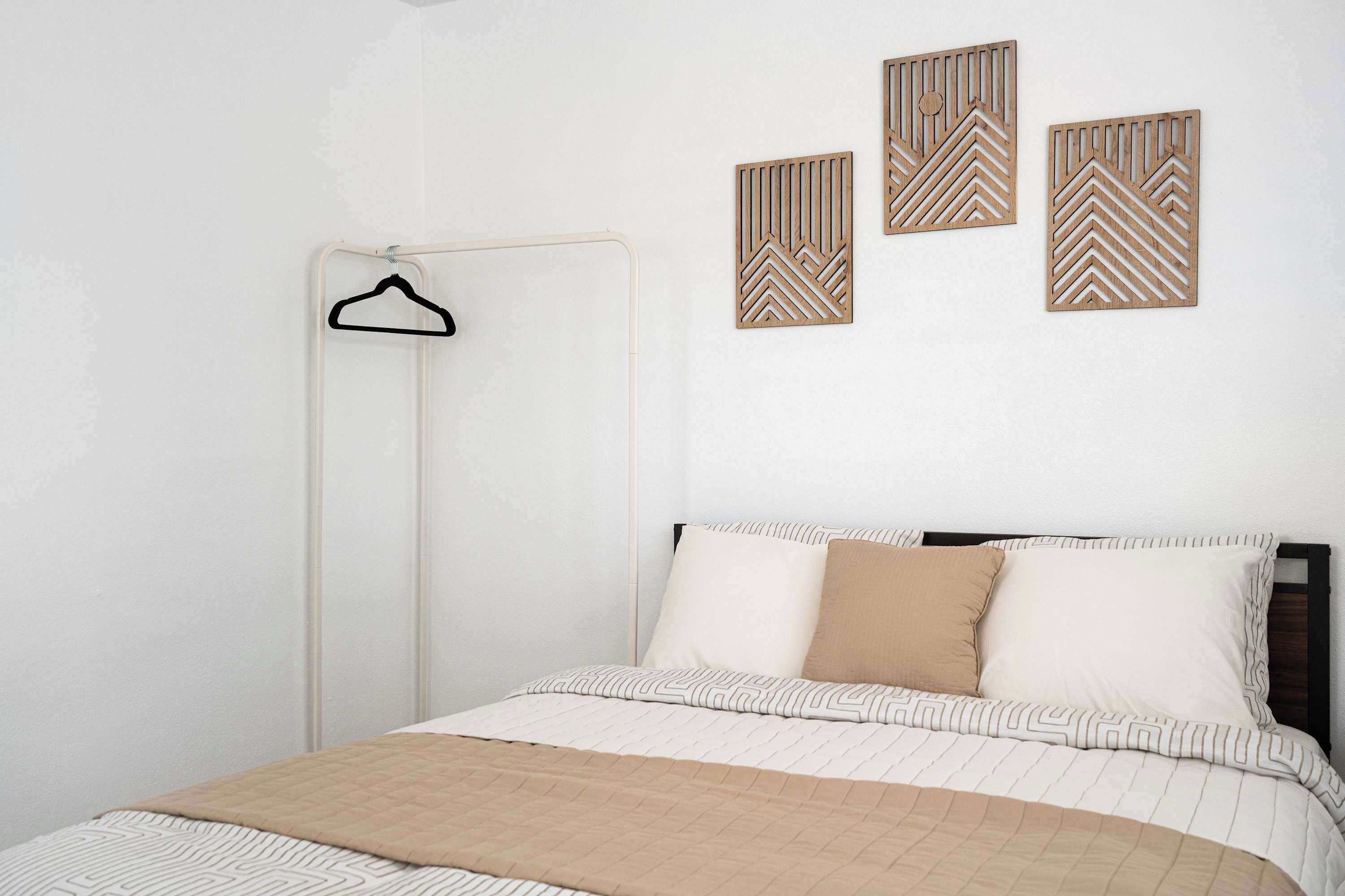 Ein Schlafzimmer mit einem Bett, einem Hängekleiderschrank und drei Wanddekorationen.