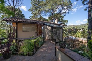 Ein Haus mit Ziegeldach, einem Balkon mit Geländer und Blick auf einen bewaldeten Bereich.